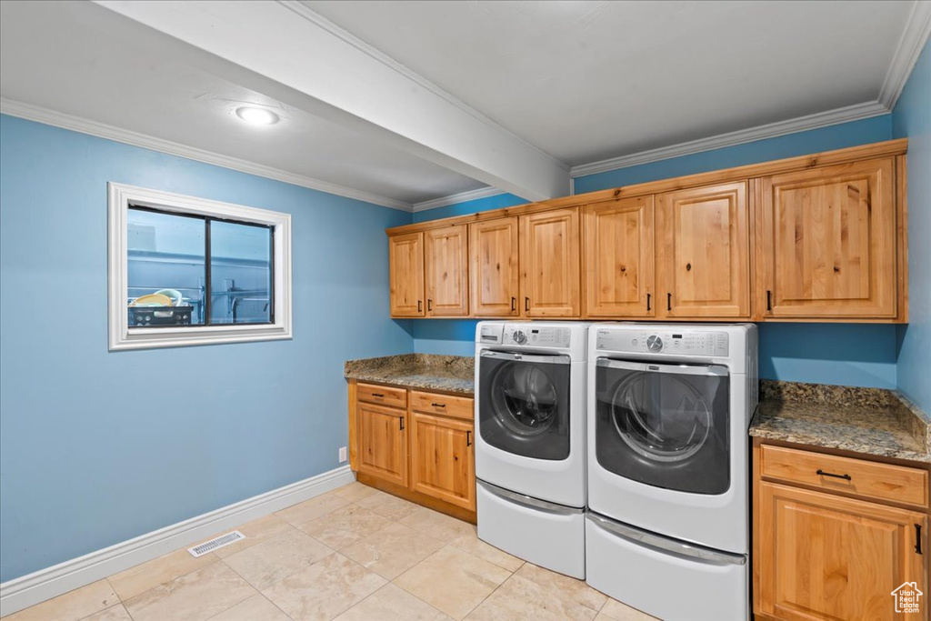 Washroom featuring cabinet space, washing machine and dryer, baseboards, and crown molding