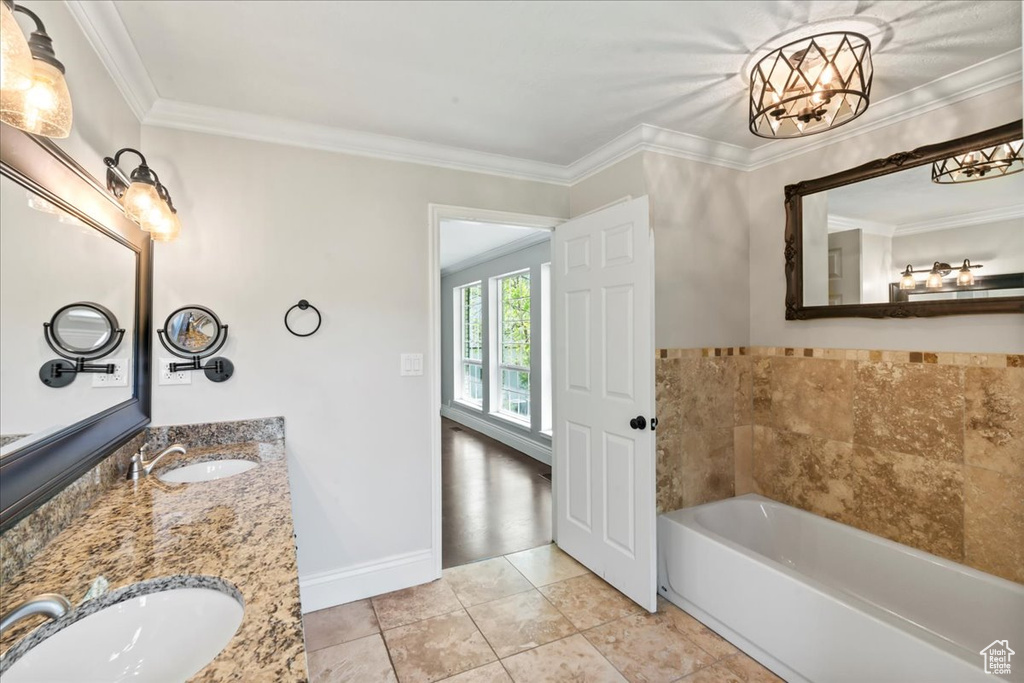 Full bath featuring a garden tub, ornamental molding, double vanity, and baseboards