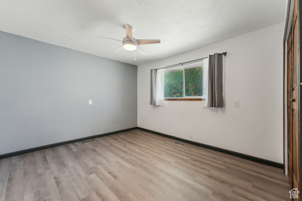 Spare room with ceiling fan, wood finished floors, and baseboards