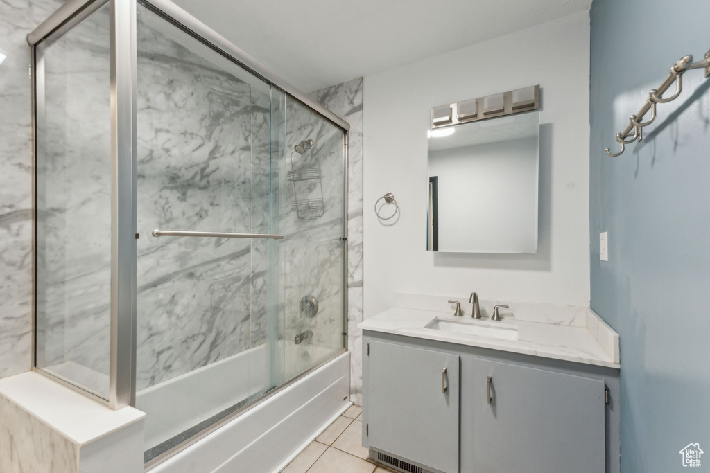 Bathroom featuring tile patterned floors, vanity, and combined bath / shower with glass door