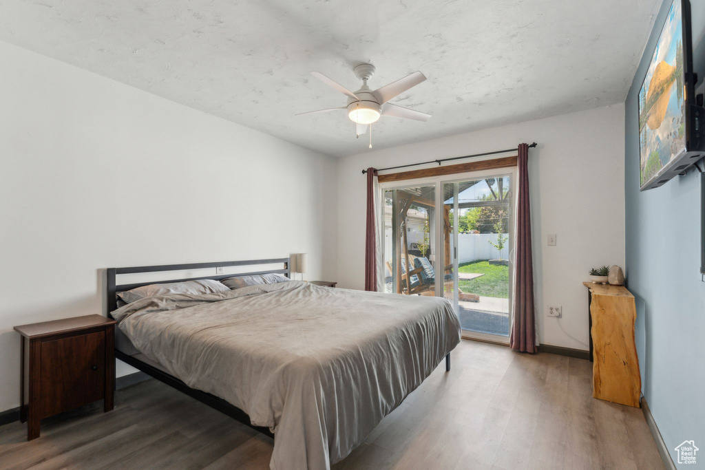 Bedroom with access to outside, wood finished floors, baseboards, and a ceiling fan