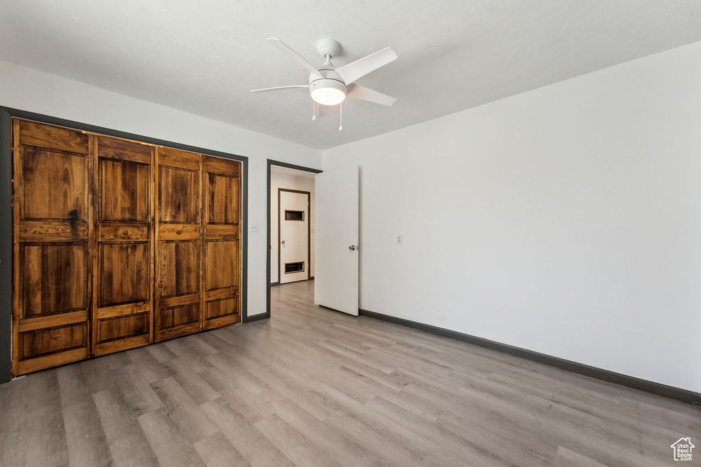 Unfurnished bedroom with light wood-style flooring, baseboards, and a ceiling fan