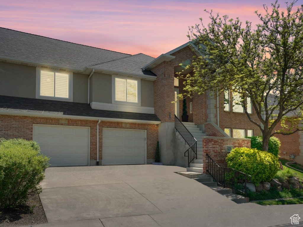 View of property featuring concrete driveway, an attached garage, stairway, and brick siding