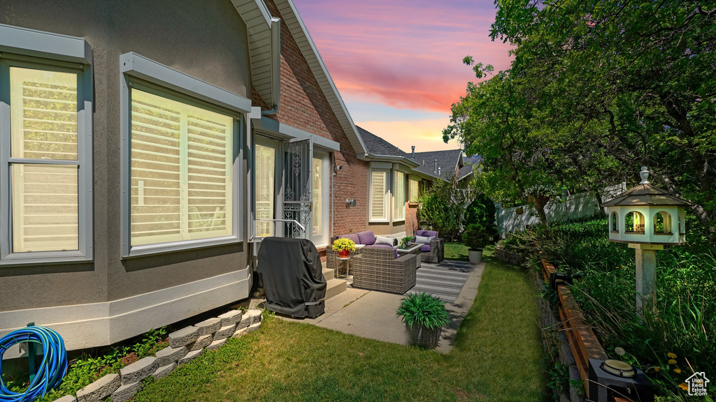 View of side of home with a patio, an outdoor hangout area, brick siding, and stucco siding