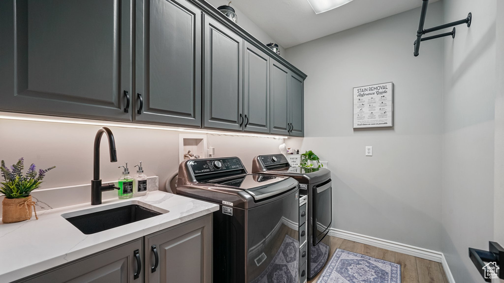 Laundry room with washing machine and dryer, cabinet space, wood finished floors, and baseboards