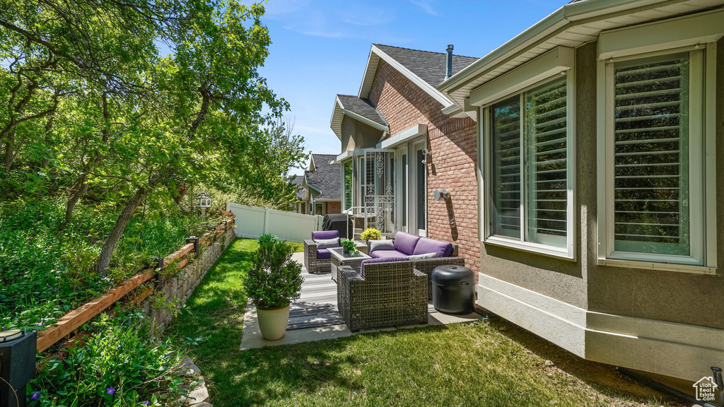 View of property exterior with a fenced backyard, outdoor lounge area, a patio area, and brick siding