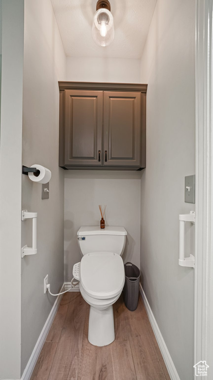 Bathroom with wood finished floors, baseboards, and toilet