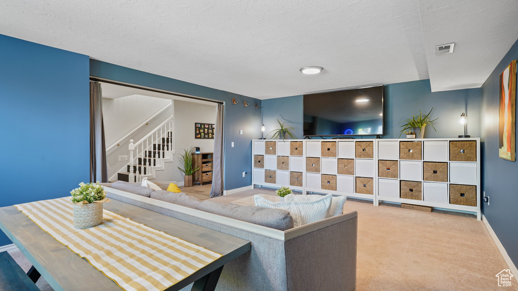 Carpeted living area featuring stairway, baseboards, and a textured ceiling