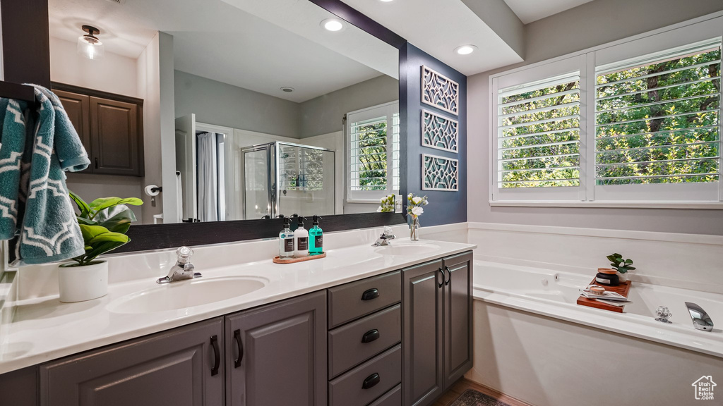 Full bath featuring a stall shower, double vanity, a bath, and recessed lighting