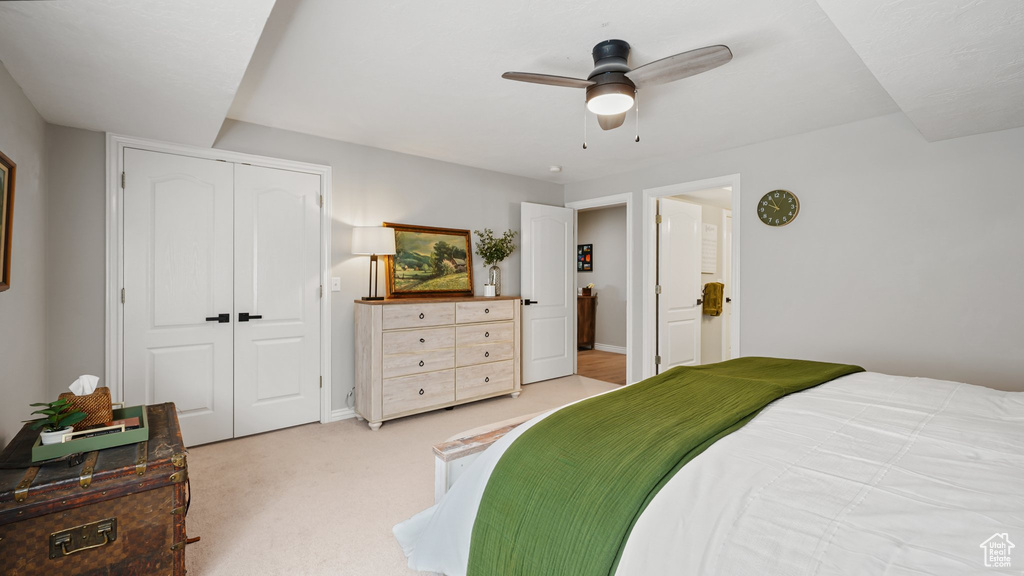 Bedroom with a closet, light colored carpet, ceiling fan, and baseboards