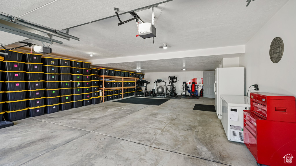 Garage with a garage door opener and freestanding refrigerator
