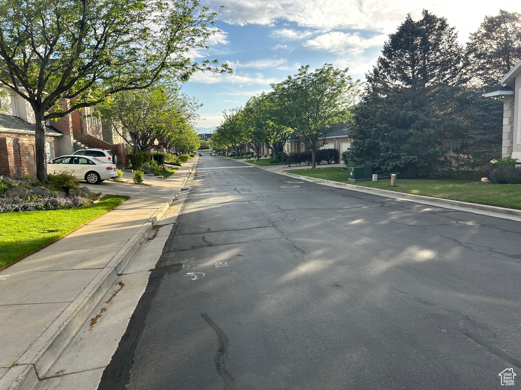 View of asphalt street with curbs, a residential view, and sidewalks