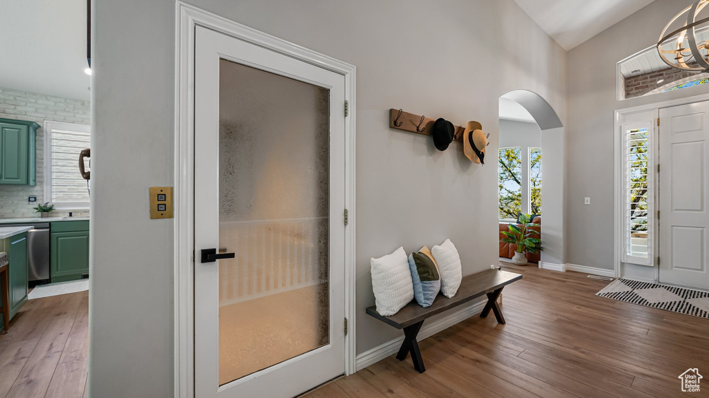 Foyer featuring light wood finished floors, arched walkways, a chandelier, baseboards, and high vaulted ceiling