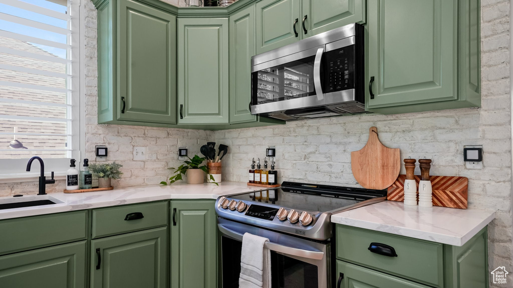 Kitchen with stainless steel appliances, green cabinetry, a sink, and healthy amount of natural light