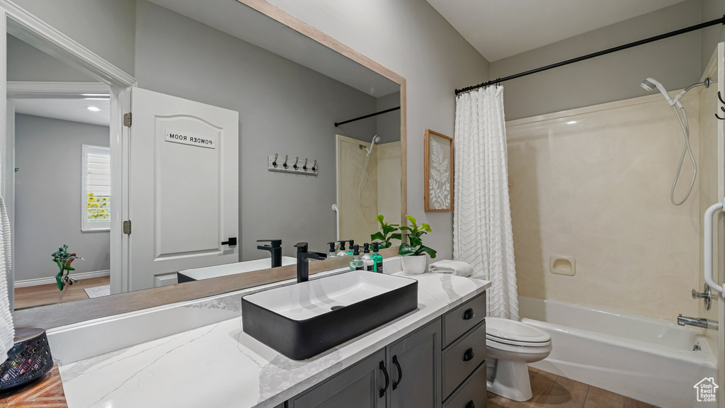 Bathroom with shower / bathtub combination with curtain, toilet, and vanity