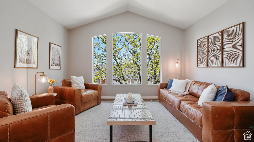 Carpeted living room featuring lofted ceiling and baseboards