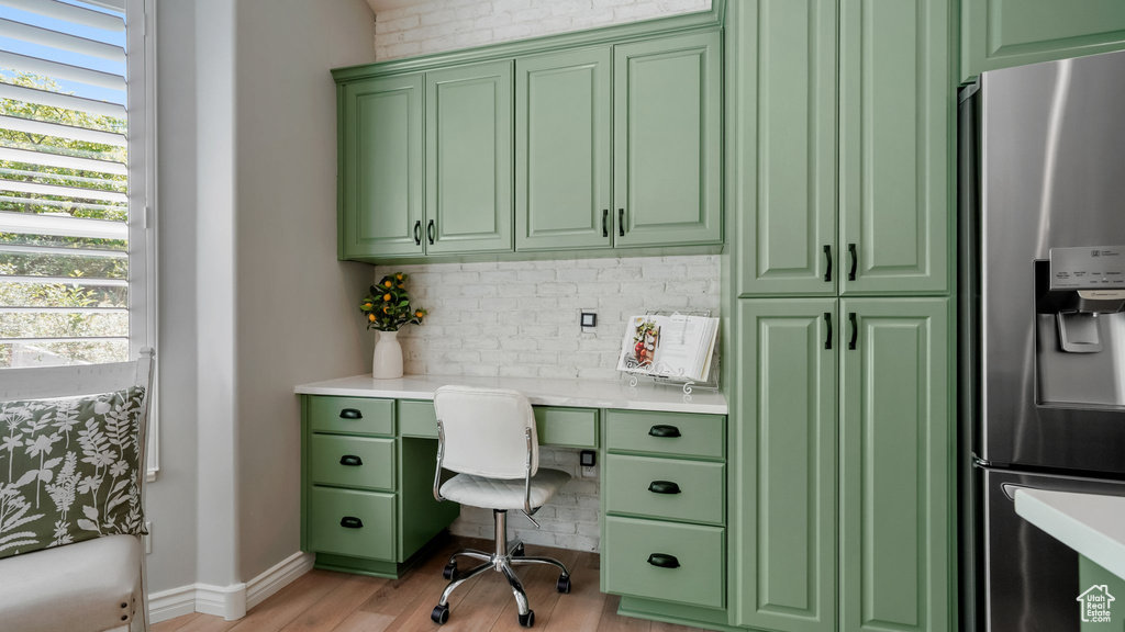 Home office featuring built in study area, light wood-style floors, and baseboards