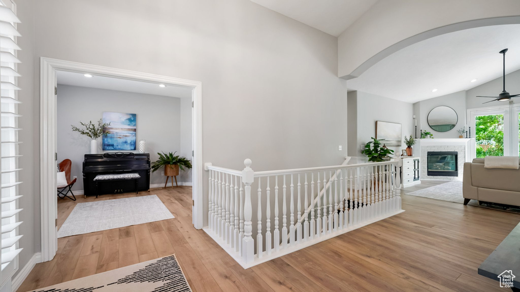 Hallway with arched walkways, light wood-type flooring, high vaulted ceiling, recessed lighting, and baseboards