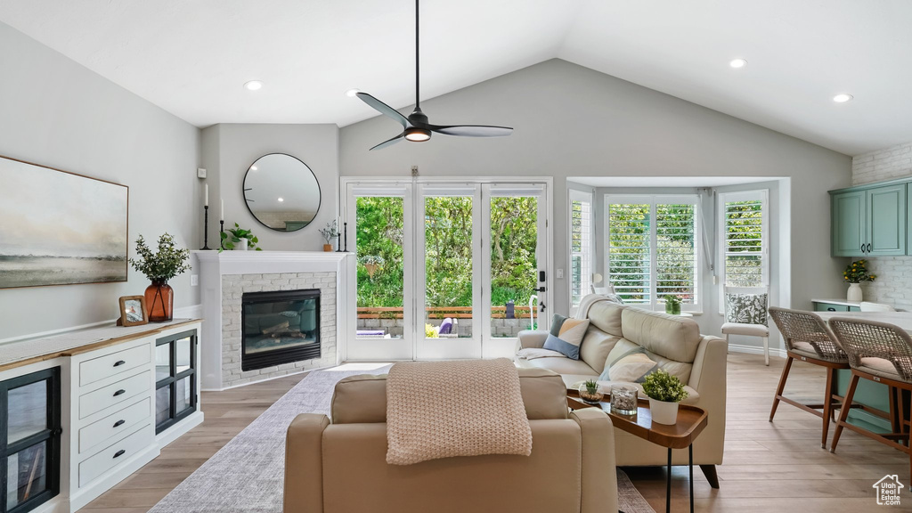 Living room featuring vaulted ceiling, ceiling fan, a fireplace, light wood-style flooring, and recessed lighting