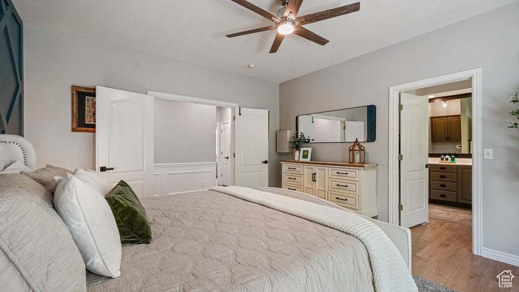 Bedroom with light wood-style flooring, ensuite bathroom, and a ceiling fan