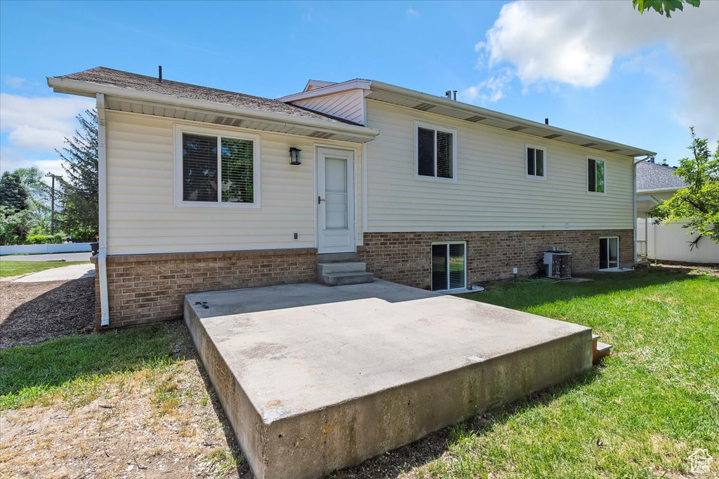 Rear view of house with entry steps, a lawn, a patio area, and central air condition unit