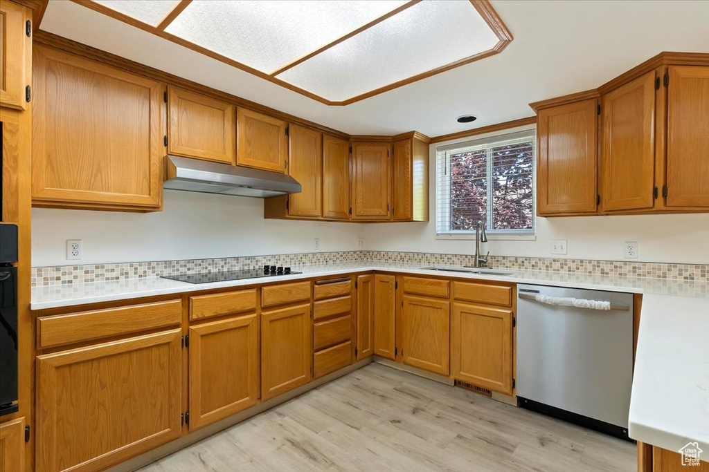 Kitchen featuring dishwasher, a sink, under cabinet range hood, and light wood-style floors