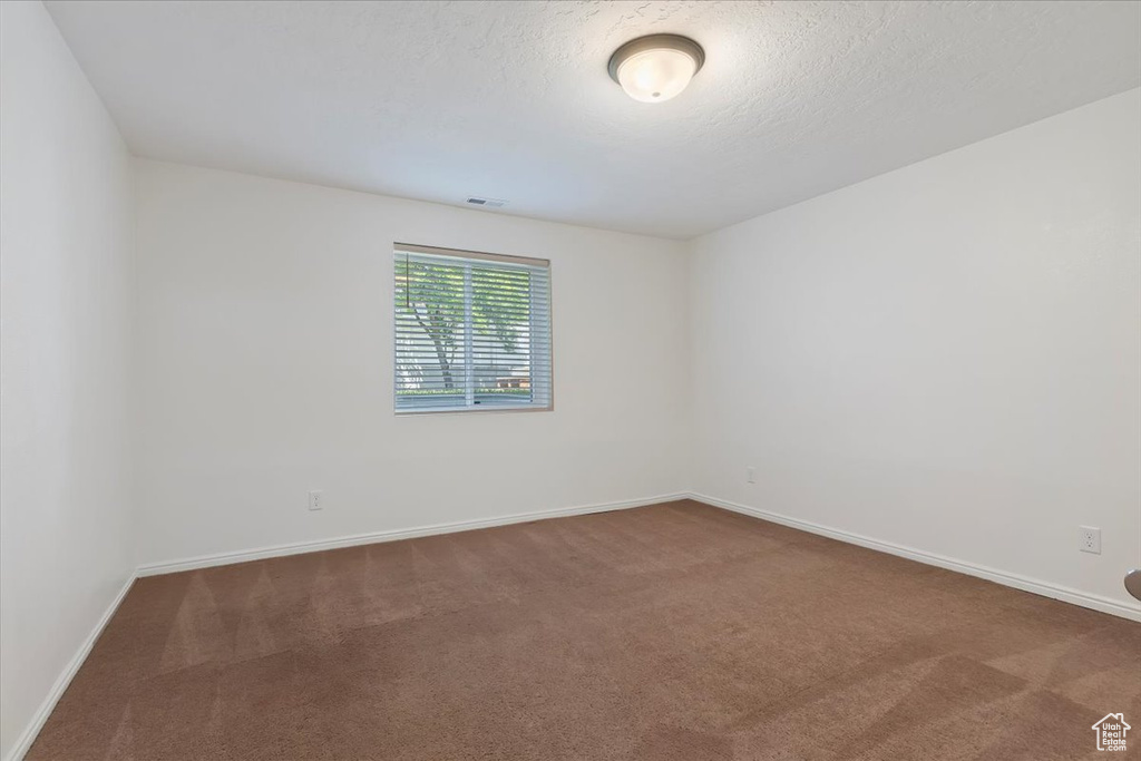 Carpeted empty room with baseboards and a textured ceiling