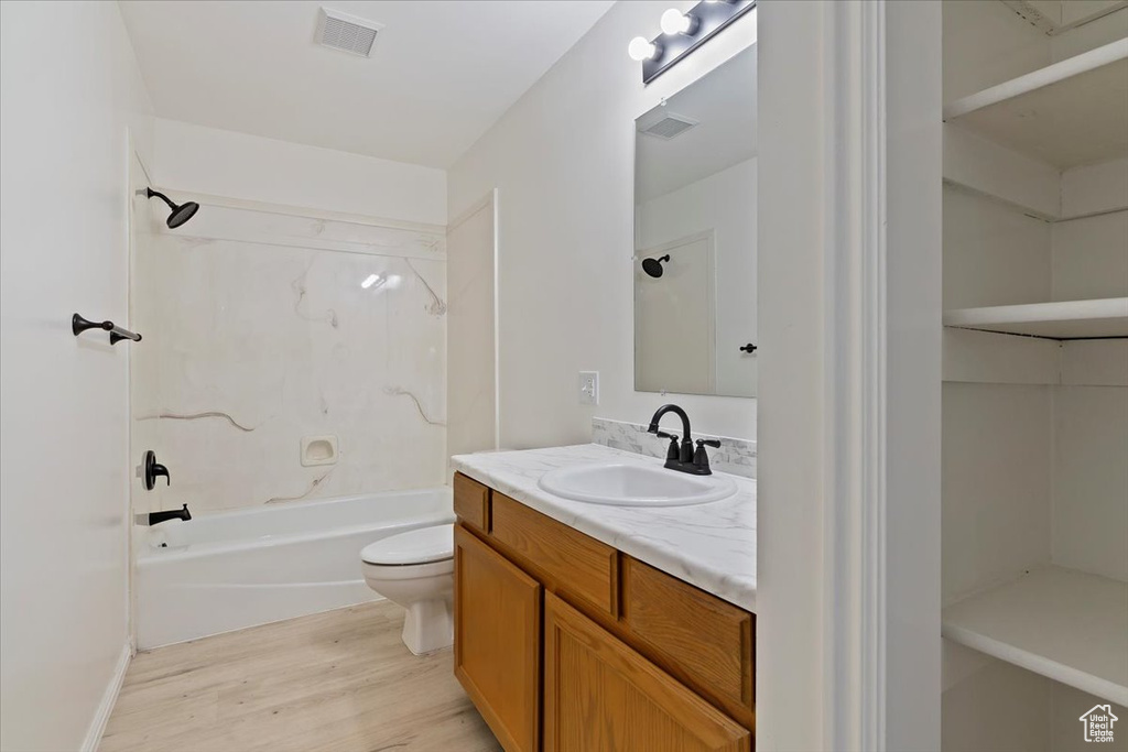 Full bath featuring wood finished floors, toilet, vanity, and shower / washtub combination