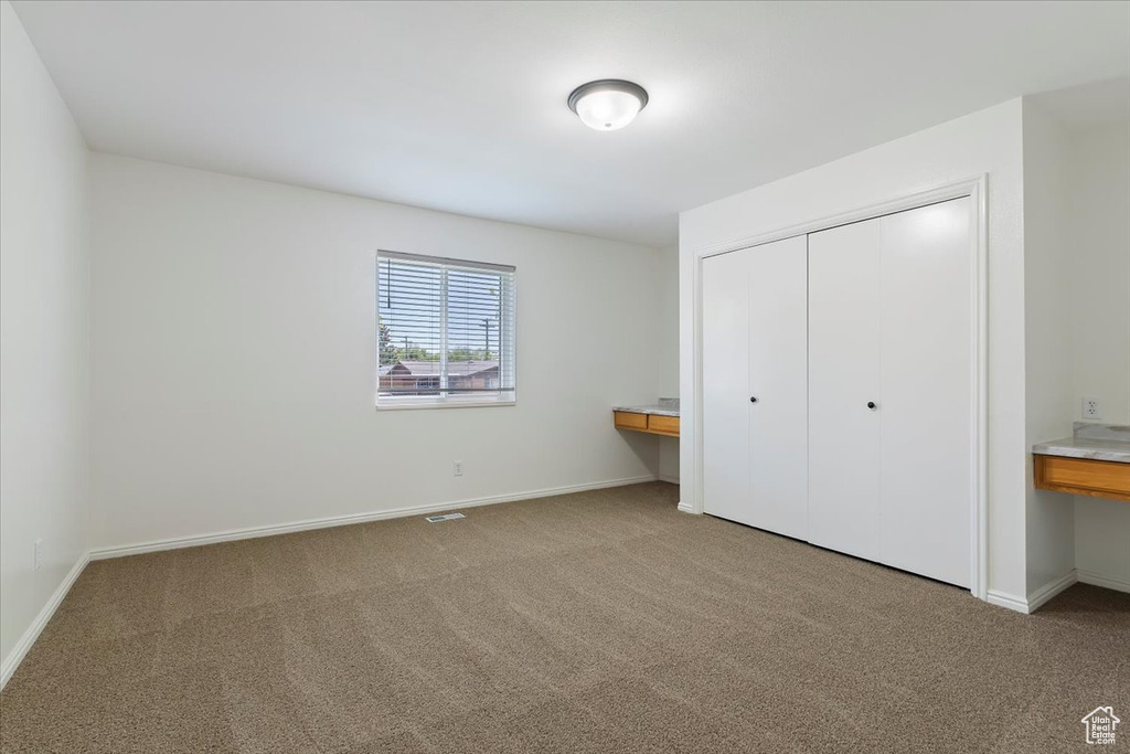 Unfurnished bedroom featuring light carpet, a closet, and baseboards