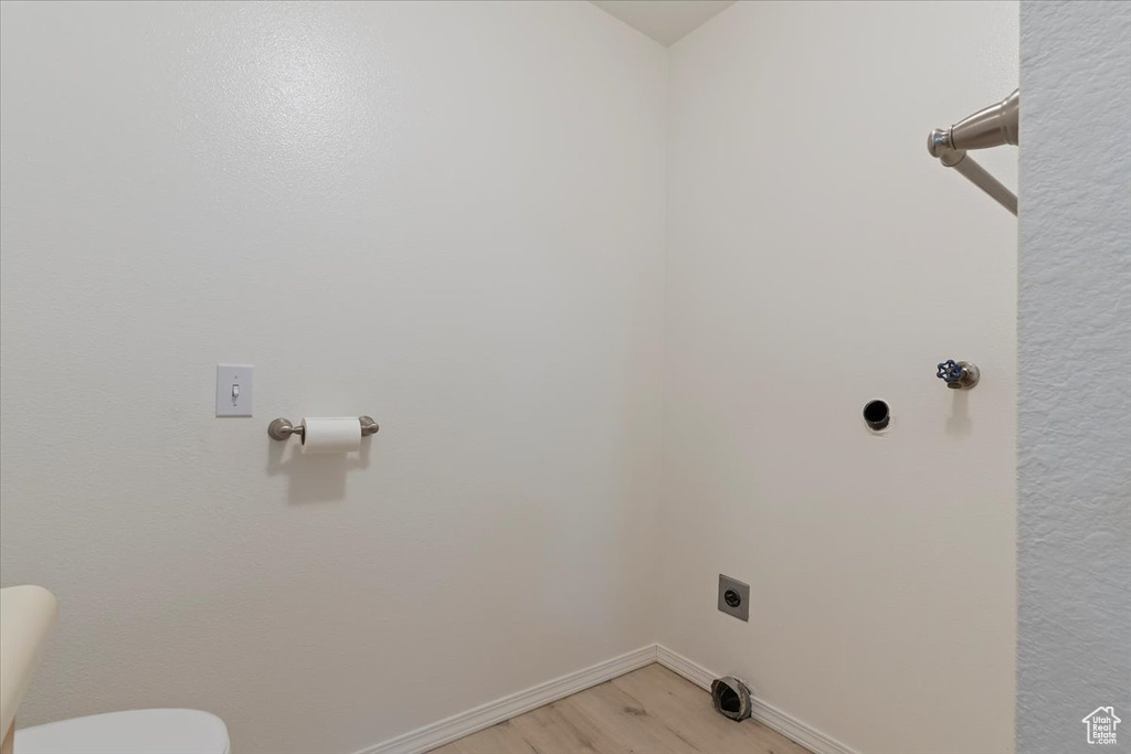 Washroom featuring electric dryer hookup, light wood-style floors, and baseboards