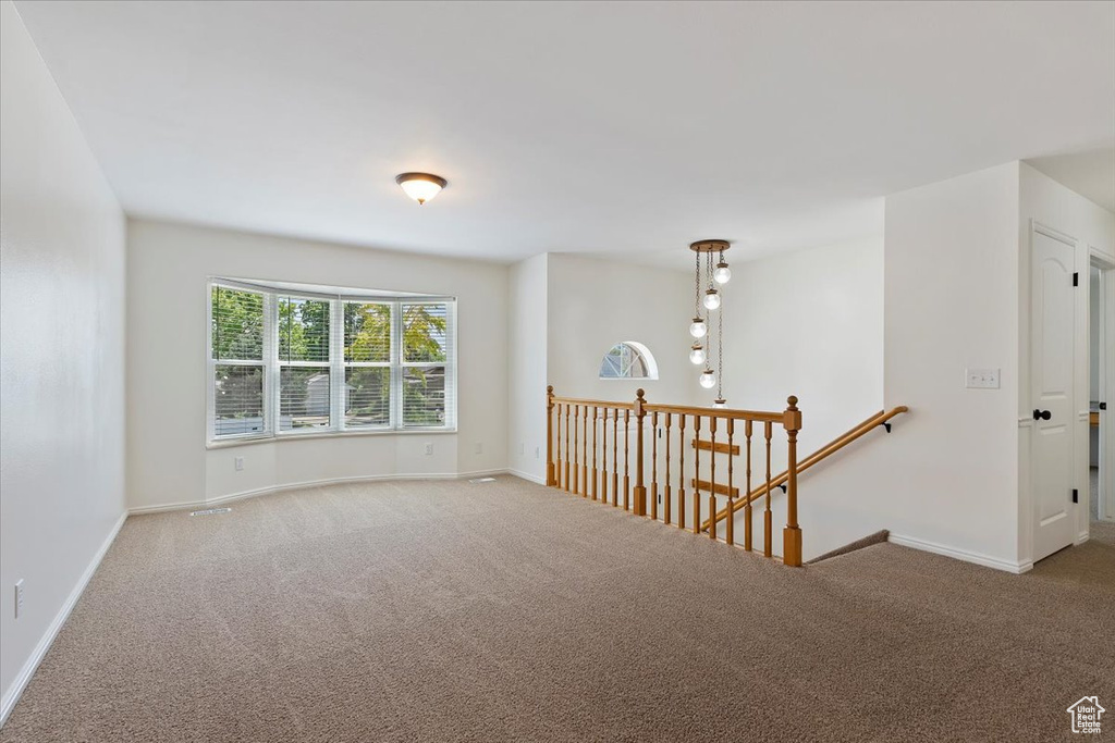 Spare room featuring carpet flooring and baseboards
