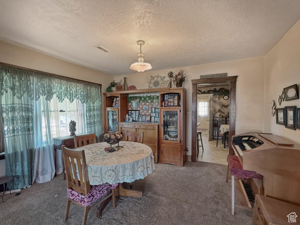 Dining area featuring light carpet and a textured ceiling