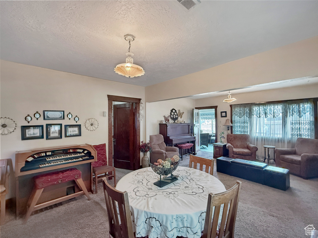 Dining space featuring carpet flooring and a textured ceiling