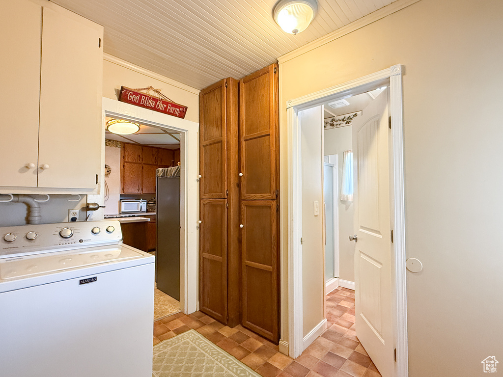 Clothes washing area featuring washer / clothes dryer, cabinet space, ornamental molding, and wood ceiling