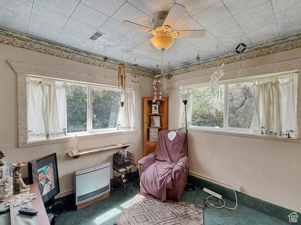 Sitting room with heating unit, carpet, and a ceiling fan