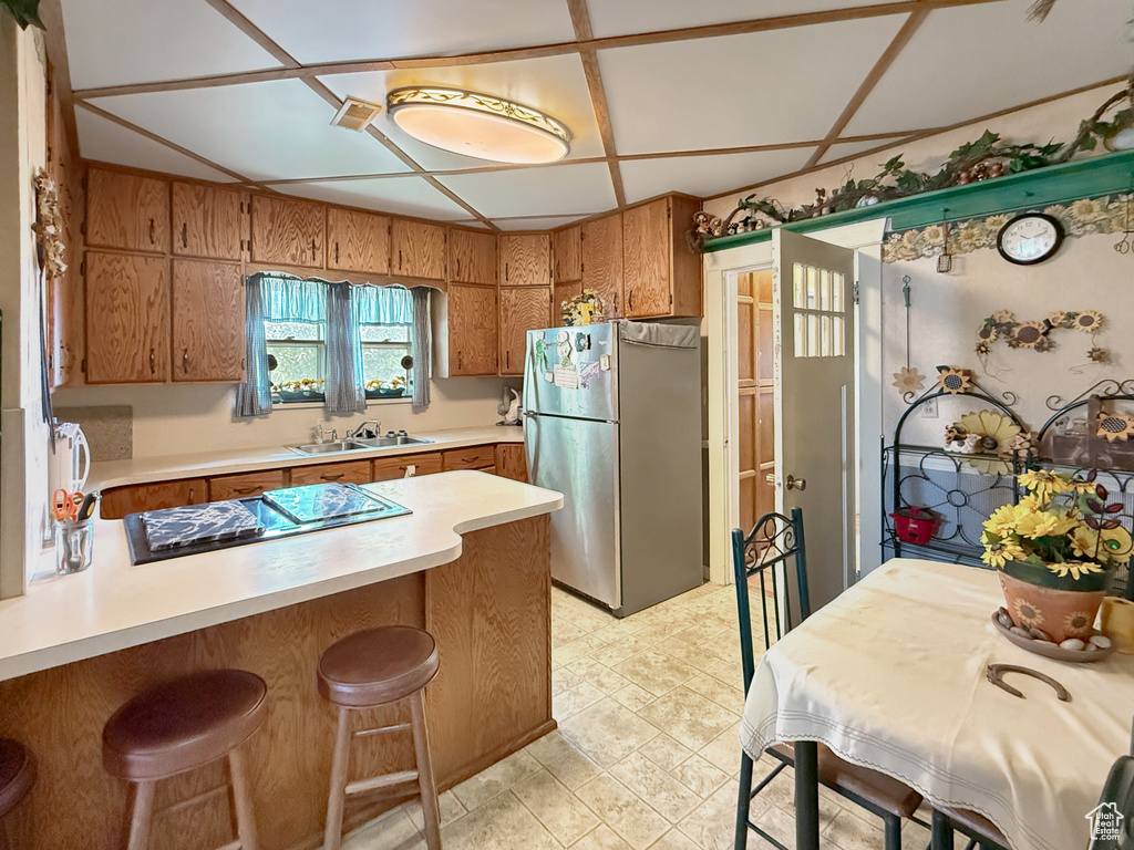Kitchen featuring freestanding refrigerator, black electric stovetop, a peninsula, and light countertops