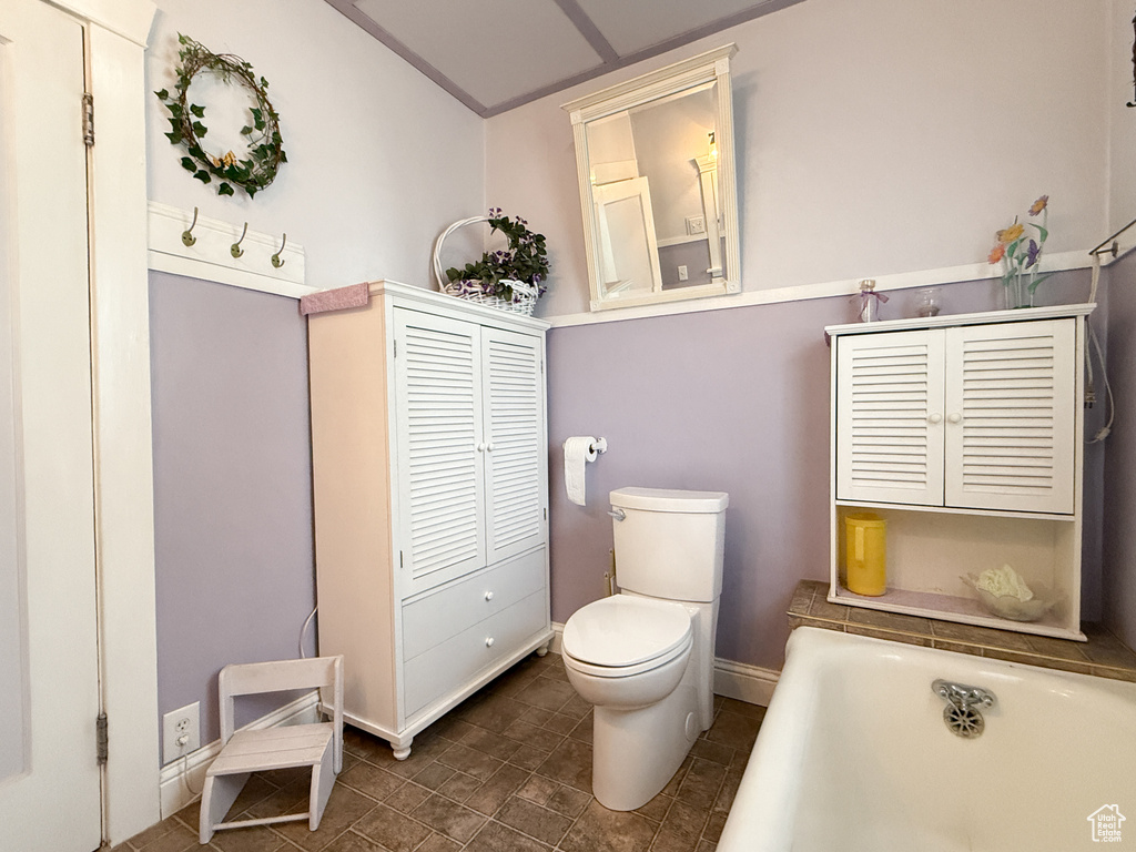 Bathroom featuring toilet, a bathtub, and baseboards