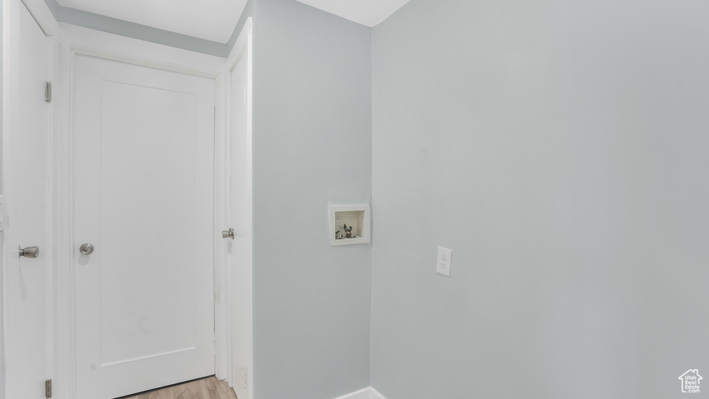 Clothes washing area with hookup for a washing machine, baseboards, and light wood-style floors