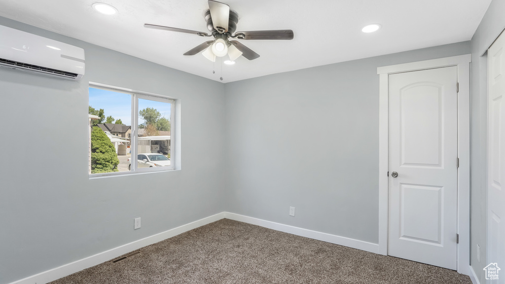 Carpeted spare room with a wall mounted air conditioner, ceiling fan, baseboards, and recessed lighting