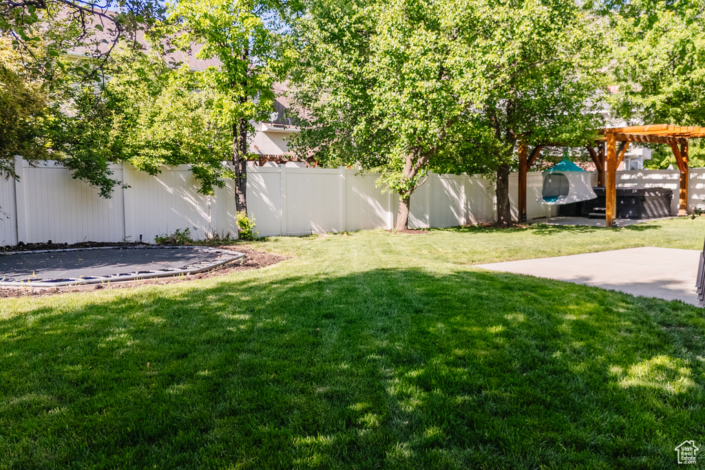 View of yard with a trampoline, a patio, and a pergola