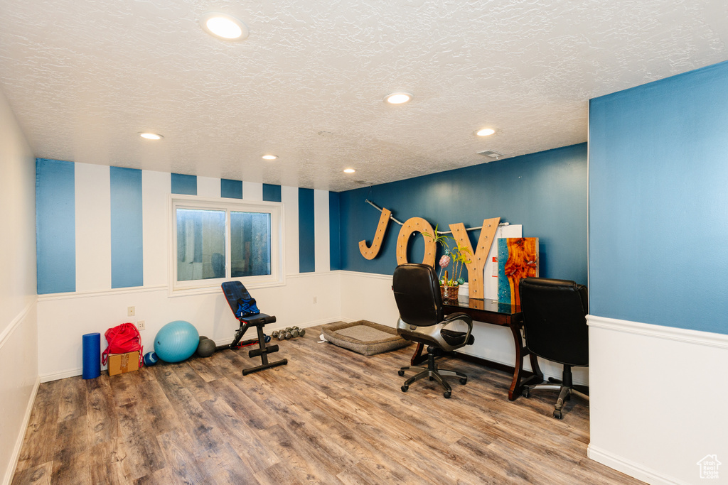 Workout room featuring wood finished floors, a textured ceiling, recessed lighting, and baseboards
