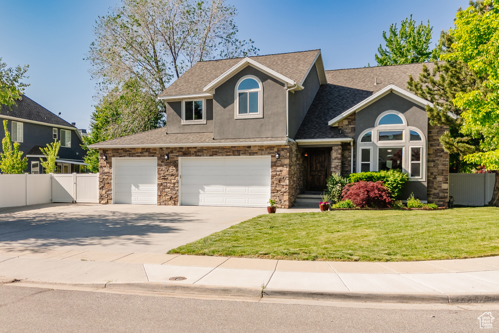 View of front of house featuring stucco siding, roof with shingles, driveway, a garage, and stone siding