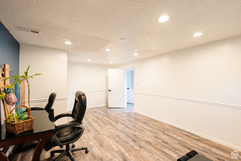 Office space featuring a textured ceiling, recessed lighting, light wood-style flooring, and baseboards
