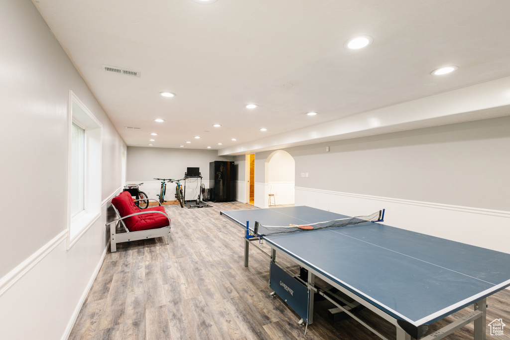 Recreation room with wood finished floors, recessed lighting, arched walkways, and baseboards