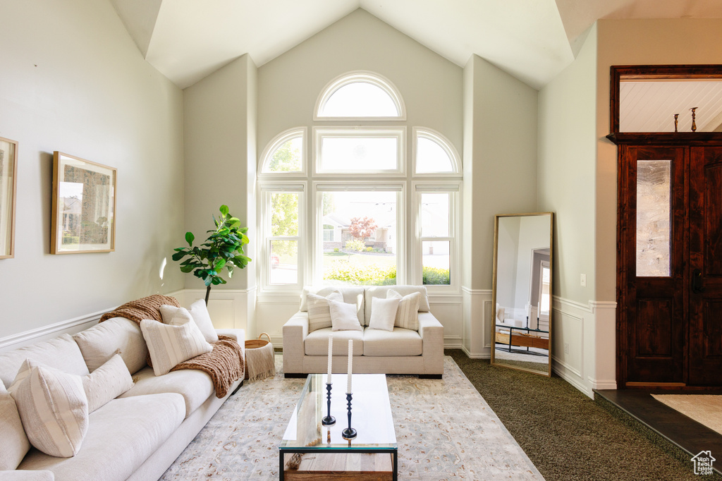 Living area with wainscoting, high vaulted ceiling, and a decorative wall