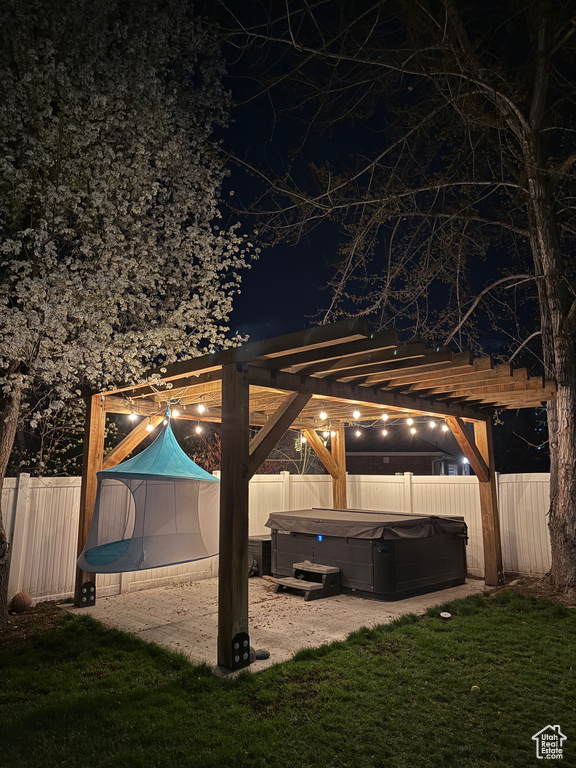 Patio at twilight with a hot tub and a pergola