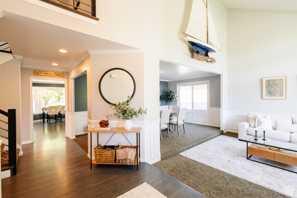 Living area with ornamental molding, healthy amount of natural light, dark wood-style floors, recessed lighting, and a wainscoted wall