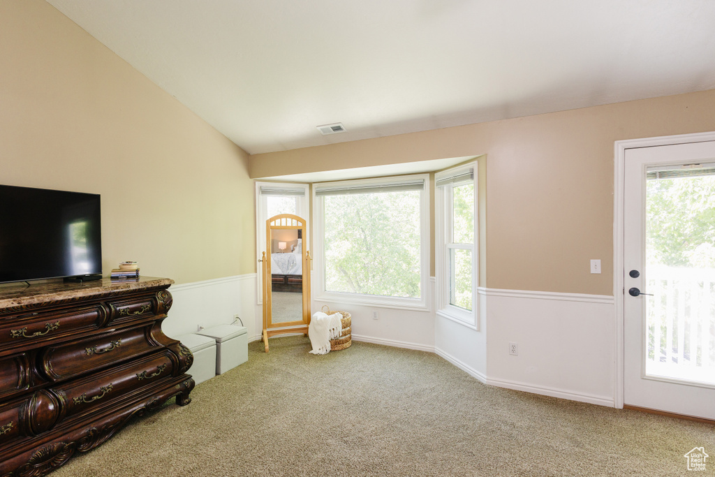 Carpeted living area with healthy amount of natural light, vaulted ceiling, and baseboards