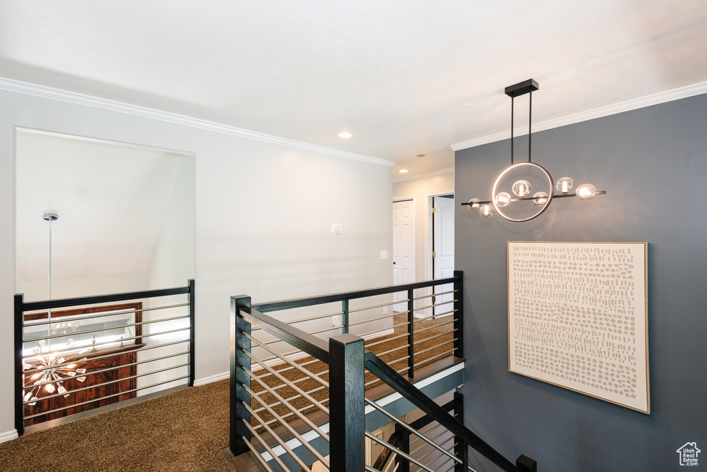 Hallway with an upstairs landing, ornamental molding, a chandelier, carpet flooring, and baseboards