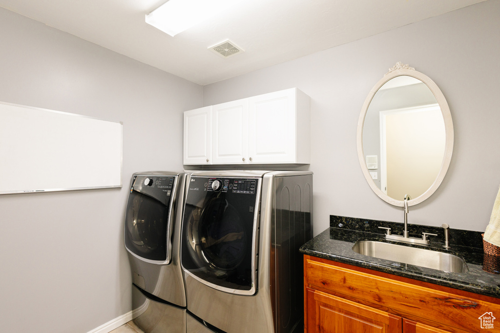 Washroom with washing machine and dryer, cabinet space, and baseboards